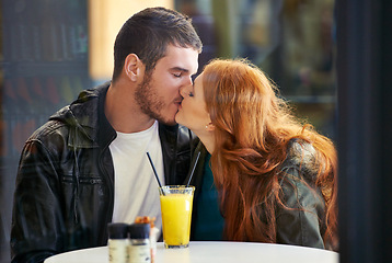 Image showing Couple, date and kiss with romance, cafe or restaurant with orange juice and happiness together. Man, woman and love for relationship, care and smile for flirting on break for relax or bonding