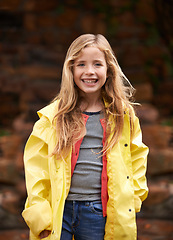 Image showing Portrait, smile and happy girl in raincoat, winter and outdoors for cold weather. Child, joyful or relax in nature for autumn or rain on vacation in Scotland, holiday or outside for youth or travel