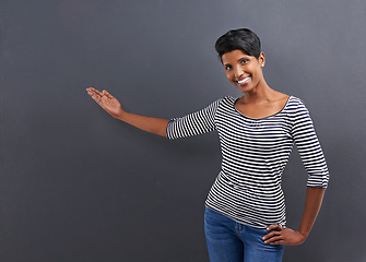 Image showing Happy woman, portrait and presentation with advertising or marketing on a gray studio background. Female person or Indian with smile for notification, alert or special deal on fashion or mockup space