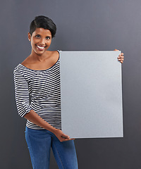 Image showing Happy woman, portrait and presentation with poster for advertising or marketing on a gray studio background. Young female person or Indian with smile, billboard or notification sign on mockup space