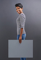 Image showing Happy woman, portrait and presentation with billboard for marketing or advertising on a gray studio background. Young female person or Indian with smile, poster or sign for message on mockup space