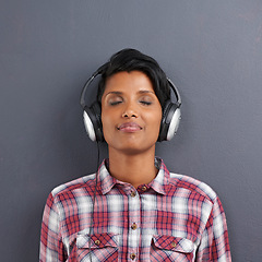 Image showing Woman, relax and listening with headphones for music or podcast on a gray studio background. Calm, young female person or Indian with smile or enjoying audio sound track with headset on mockup space