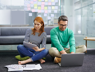 Image showing Woman, man and laptop on floor at startup with tablet, documents and thinking with teamwork in office. Business people, partnership and computer with paperwork for planning at creative media agency