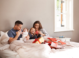 Image showing Happy family, love and gift unboxing in a bed in celebration of birthday, event or mothers day at home together. Support, care and kids with parents in a bedroom with thank you, present or bonding