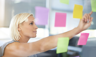 Image showing Woman, glass and board with pointing, thinking and notes for planning, proposal and idea development. Person, wall and paper for brainstorming process, decision or choice with smile in modern office