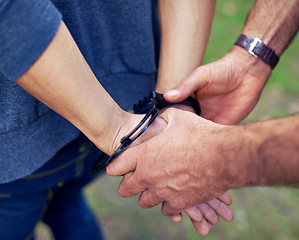 Image showing Police officer, hands and closeup to arrest person for crime with safety, legal and security service. People, law enforcement and outdoor for justice, peace or stop danger in society with handcuffs