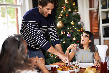 Image showing Family, Christmas and dad serving food for festive lunch, bonding and eating together in home. Holiday, celebration and happy people at table with laugh, drinks and xmas dinner tradition with smile