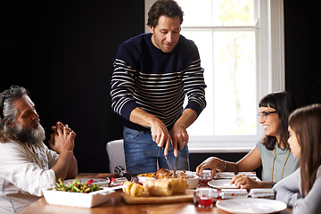 Image showing Family, Christmas and dad carving turkey for festive lunch, bonding and eating together in home. Holiday, celebration and happy people at table with food, drinks and xmas dinner tradition with smile