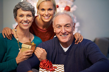 Image showing Christmas, gift and senior family in portrait with love, happy and gratitude for holiday and tradition at night. Face of elderly mother, father and daughter with present for a celebration at home
