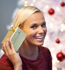 Image showing Christmas, gift and excited woman listening with holiday surprise, celebration and tradition at night. Portrait of a young person by tree and bokeh lights with present, box and thanksgiving at home