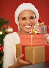 Image showing Christmas, present and woman in portrait for holiday, celebration and tradition on a red or wall background. Excited, happy and young person by tree with bokeh lights, gift or giving box at home
