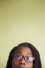 Image showing Teenager, glasses and looking up in studio of education, learning and knowledge on a green background. Boy, child or student thinking, vision and creative ideas or reading information on mockup space