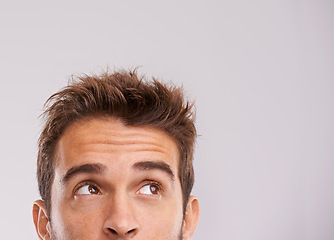 Image showing Mockup, eyes up and man with thinking for information, promotion and presentation in studio. Male person, idea and vision on white background for inspiration, daydreaming or thoughtful direction