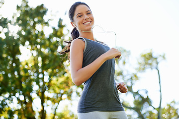 Image showing Young woman, running and music in portrait in park, happy and streaming audio for exercise in nature. Lady, smile face or wellness with earphones for training, fitness or health in outdoor in summer