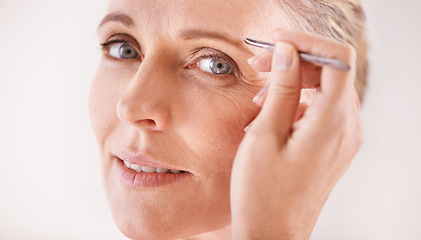 Image showing Beauty, tweezers and portrait of a mature woman on white background for facial grooming or hair removal. Spa, salon and face of female model in studio plucking or tweezing eyebrows for skincare glow