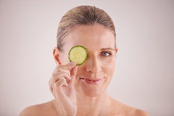 Image showing Beauty, cucumber and portrait of mature woman in studio for health, wellness or natural routine. Smile, skincare and female person with organic vegetable for dermatology treatment by white background