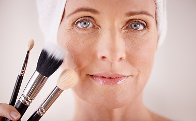 Image showing Portrait, mature woman and makeup with brushes, cosmetics and dermatology on grey studio background. Face, person and model with product and tool with wellness and skincare with treatment or grooming