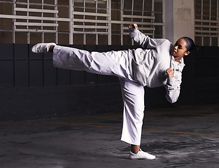 Image showing Martial arts, woman and fitness in building for training with kick, exercise and practice for competition at night. Karate, athlete and workout for self defense, discipline and technique in warehouse