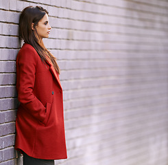 Image showing Winter, jacket and woman on wall with fashion in city for travel with cool style in red coat. Streetwear, clothes and girl outdoor on building background with confidence and pride in New York spring