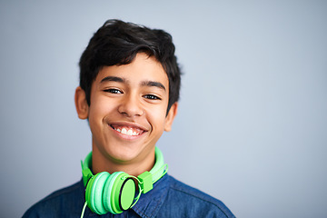 Image showing Child, portrait and smile with headphones for music entertainment as school student for podcast, track or listening. Boy, face and streaming audio in studio on grey background, radio or mockup space