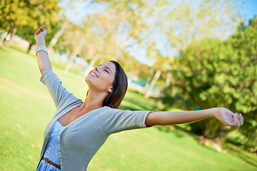 Image showing Happy woman, freedom and nature for outdoor wellness, travel and fresh air in environment and summer. A young and casual person wit eyes closed and stretching arms for celebration and excited in park