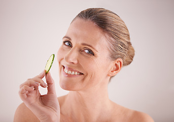 Image showing Mature woman, portrait and cucumber for skincare in studio with healthy skin, organic detox and facial wellness. Model, person and happy face with fruit for anti aging treatment on white background