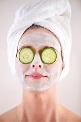 Image showing Spa, woman and cucumber facial for skincare in studio with skin mask, organic detox or cosmetics with towel. Model, person or face with fruit for anti aging treatment or self care on white background