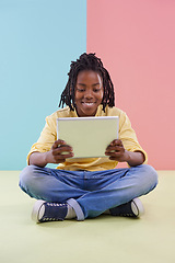 Image showing Teenager, reading and tablet in studio for online education, e learning and creative games on floor. Kid, student or african boy with digital technology in pastel color or blue and pink background