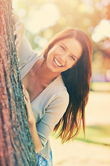 Image showing Woman, park and tree with smile, portrait and happiness with joy and green fun for nature. Lady, laugh and sun with grass, forest and bokeh for exited playful summer with optimism and sunshine