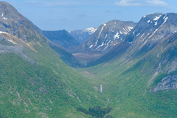 Image showing Serene valley amongst majestic mountains under a clear blue sky
