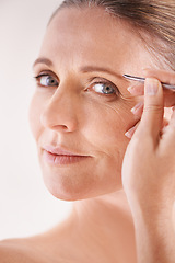 Image showing Beauty, tweezers and portrait of a mature model on white background for facial grooming or hair removal. Spa, salon and face of female person in studio plucking or tweezing eyebrows for skincare glow