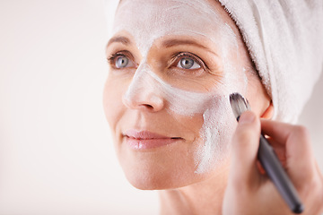 Image showing Mature woman, face mask with brush for smile in studio for skincare or anti aging on self care, wellness and fresh skin. Closeup, female person and glow with happiness for facial and beauty or luxury