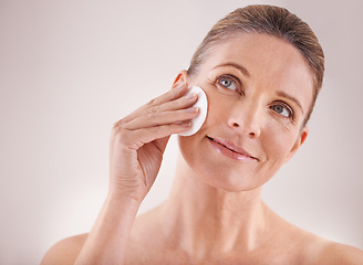 Image showing Mature woman, smile and cotton for skincare in studio with facial cleansing, cosmetics and skin treatment. Model, person and swab for face detox, makeup removal and natural beauty on white background