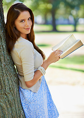 Image showing Park, portrait and woman with smile for book, novel and fiction in nature to relax by tree outdoor. Adult, girl and female person with confidence for knowledge, happy and joy for reading in summer