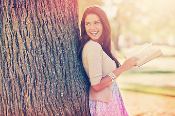 Image showing Tree trunk, portrait and woman with smile for novel, book and fiction in nature to relax in park. Adult, girl and female person with confidence for knowledge, happy and joy for reading in summer