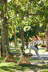 Image showing Woman, nature and listening to music for stretching in park, fitness and commitment to training for healthy body. Young lady, exercise and runner with streaming radio and morning workout in outdoor