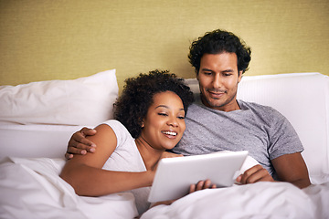 Image showing Bed, woman and man relax with tablet, cuddle and rest on soft mattress, love and romance for couple. Partners, male person and girl in bedroom, happy and together in pyjamas, break and weekend