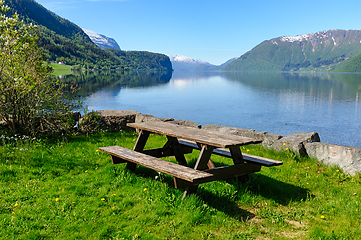 Image showing Tranquil wooden picnic table by serene norwegian fjord on sunny 