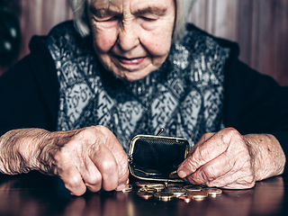 Image showing Portrait of an old woman counting money. The concept of old age, poverty, austerity.