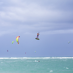 Image showing Kiteboarding. Fun in the ocean. Extreme Sport Kitesurfing. Kitesurfer jumping high in the air performing triks during kitesurfing session.