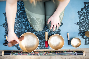 Image showing Yoga concept, meditation and sound therapy. Beautiful young caucasian woman surrounded by copper tibetan singing bowls and instruments.