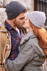 Image showing Couple, love and kiss with closeup in outdoor in against wall on cold weather, together and support in London. Affection, relationship and bonding for romance with soulmate, care and happiness