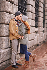 Image showing Couple, love and kiss with affection outdoor at sidewalk or against wall in cold weather, together and support in London. Relationship, date and bonding for romance with commitment, care and happy