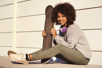 Image showing Portrait, smile and woman with skateboard in city by wall in summer for sport, fashion or relax outdoor. Happy person, skate park and gen z girl in casual clothes with headphones in South Africa