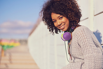 Image showing Woman, smile and portrait in city for travel, walk and break in urban for summer, fun and outdoor. African person and happy with headphones for music, streetwear and journey in town for trip