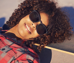 Image showing Black woman, outdoor and smile with sunglasses on skateboard for training and relax in Atlanta . Closeup, female person and skater with hobby or sport for fitness, health and fun at skatepark