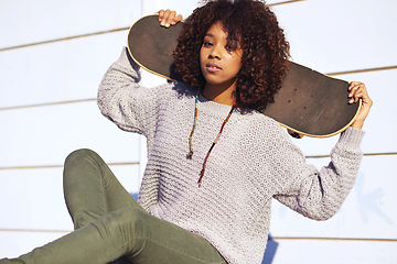 Image showing Portrait, confidence and woman with skateboard in city by wall in summer for sport, attitude or relax outdoor. Serious person, skate park and young girl in casual clothes for fashion in South Africa