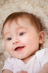 Image showing Happy, sweet and closeup of baby on blanket playing for child development and curious face. Smile, cute and young girl kid, infant or newborn relaxing and laying on bed in nursery room at home.