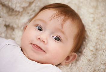 Image showing Happy, cute and face of baby on blanket playing for child development and curious facial expression. Smile, sweet and girl kid, infant or newborn relaxing and laying on bed in nursery room at home.