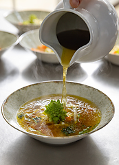 Image showing Pouring broth on fresh salad